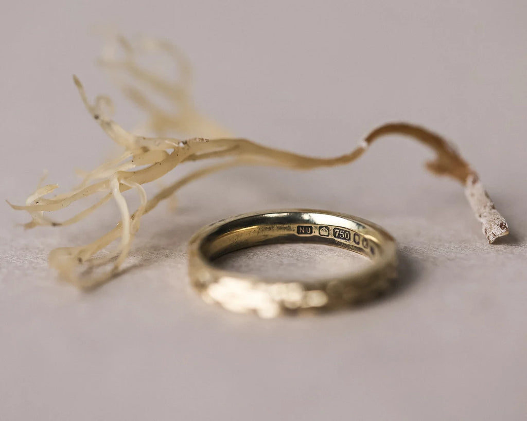 Gold ring with engraved details on a light gray background