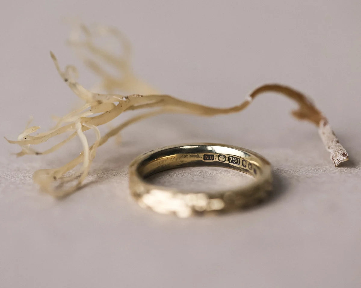 Gold ring with engraved details on a light gray background