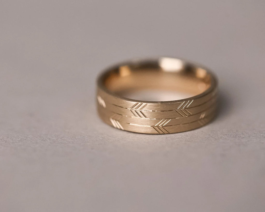 detailed double arrow pattern engraving gold band close view