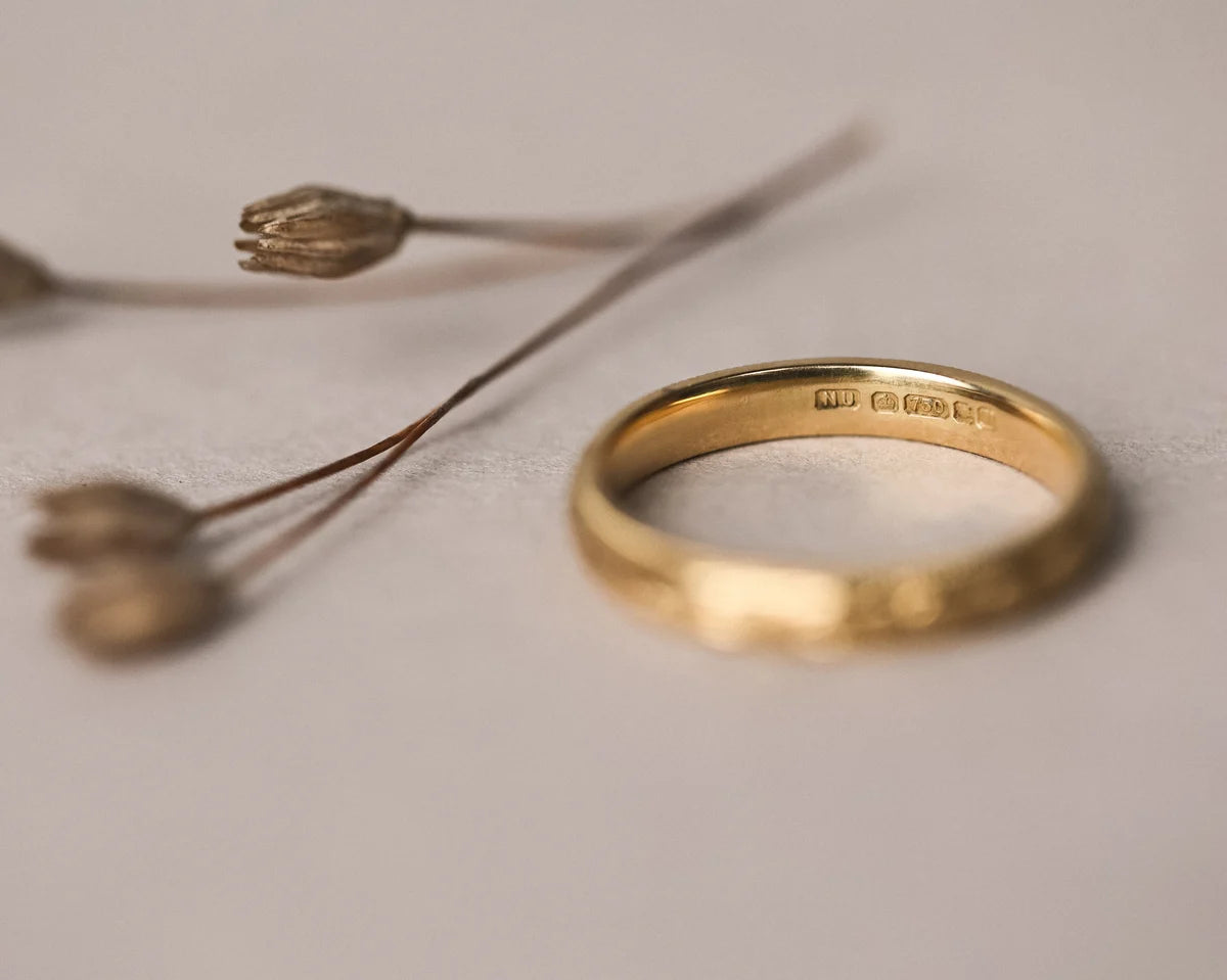 Gold ring on a light gray surface with a blurred background