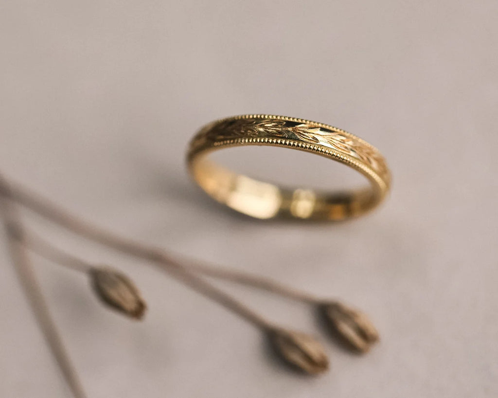 Gold ring with intricate design on a neutral background