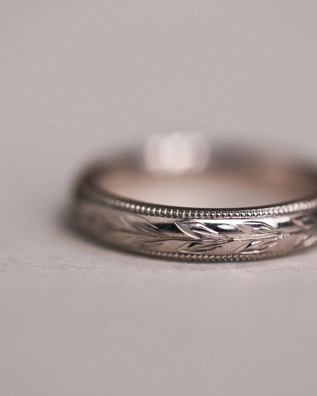 Detailed view of olive leaf engraving and fine milled edge on white gold band