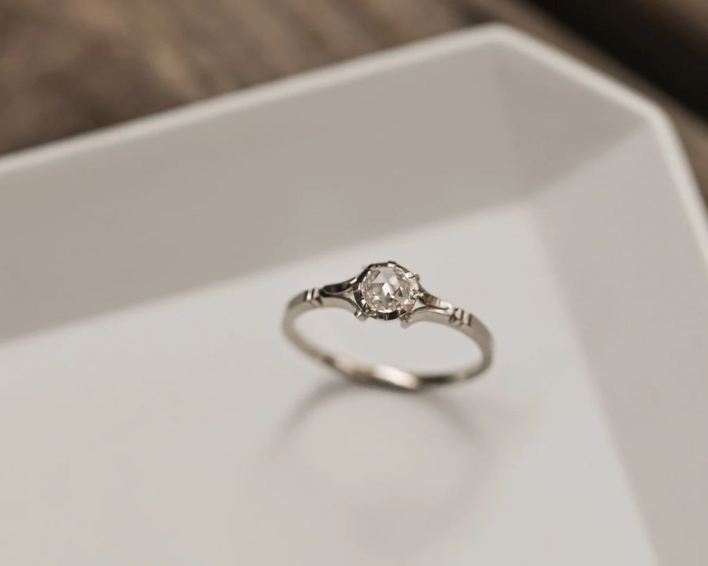 Silver ring with a diamond on a white surface