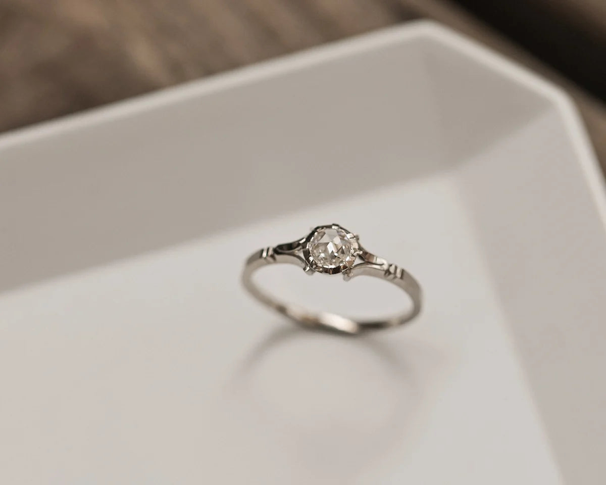 Silver ring with a diamond on a white surface