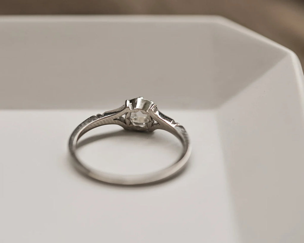 Silver ring with a diamond on a white surface