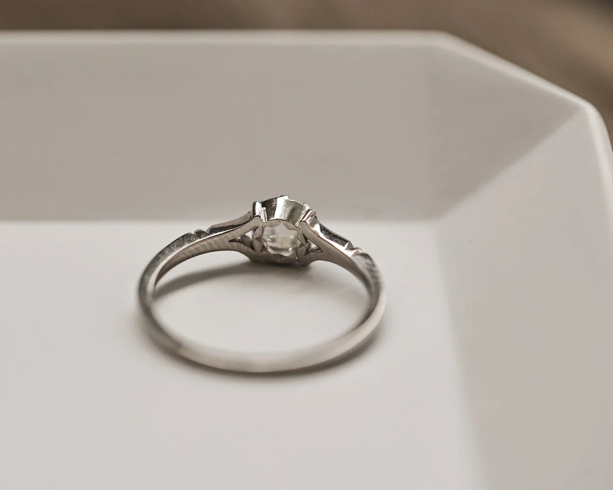 Silver ring with a diamond on a white surface