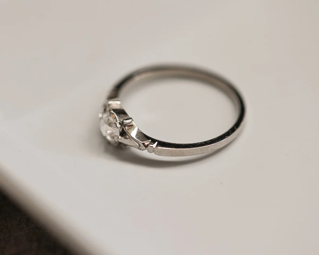 Silver ring with a diamond on a light gray background
