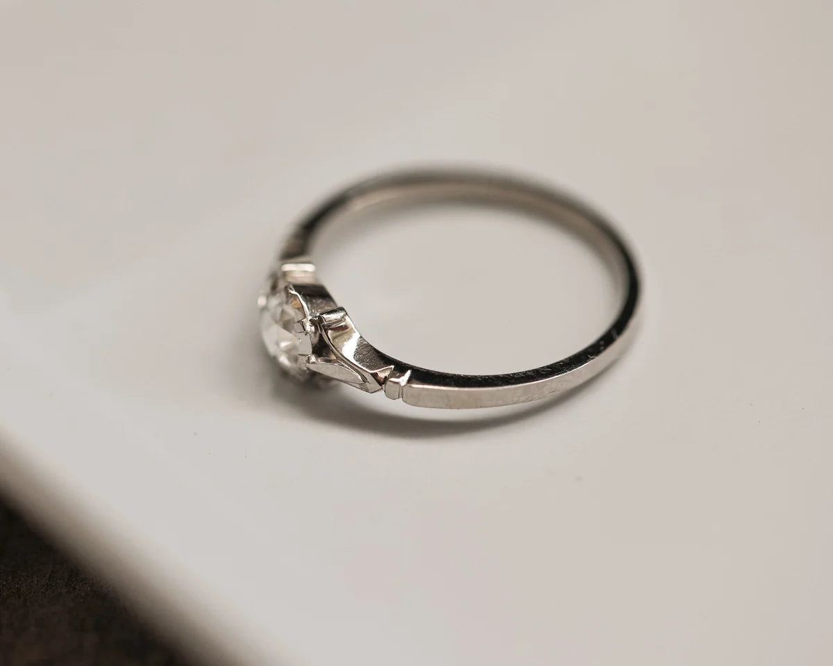 Silver ring with a diamond on a light gray background