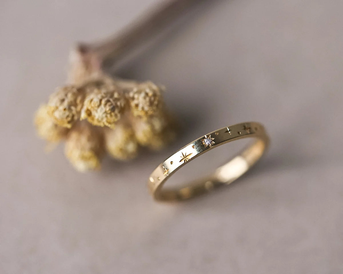 Gold ring with engraved details on a neutral background