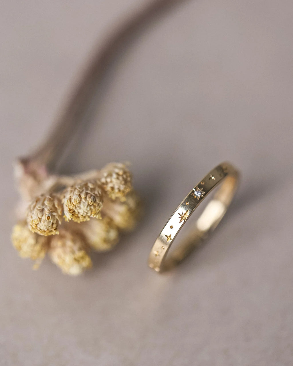 Gold ring with star and moon designs on a neutral background
