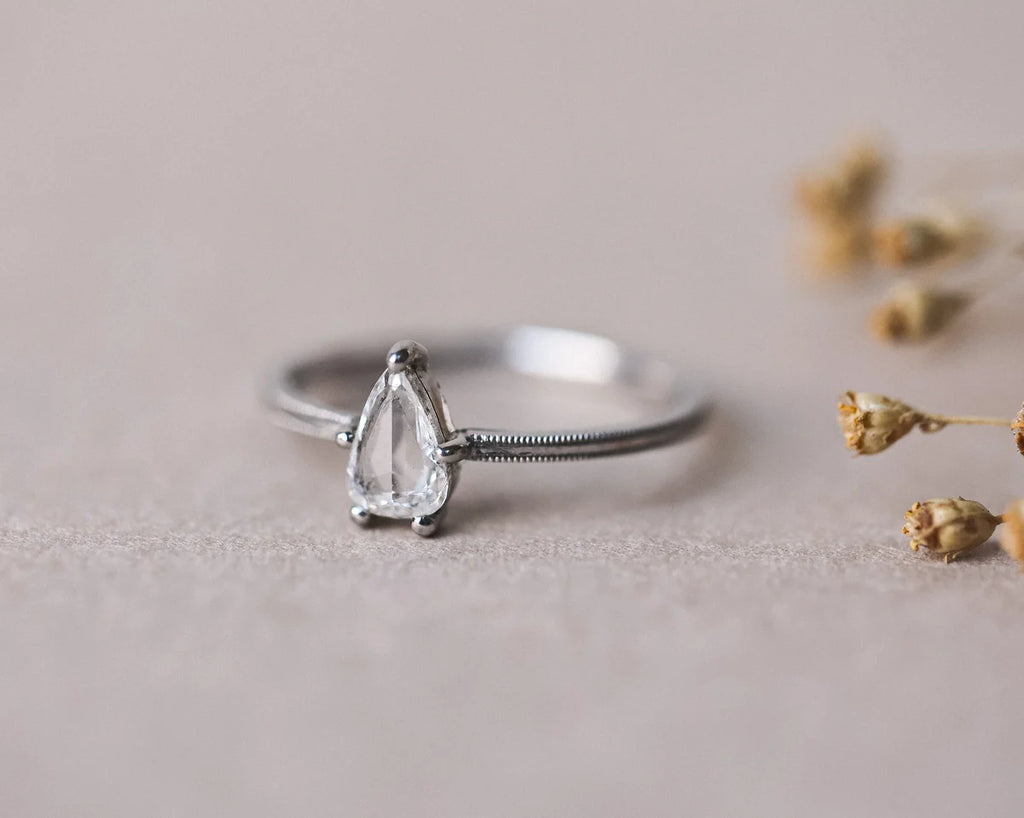 Front view of platinum pear cut diamond ring with fine milled edge
