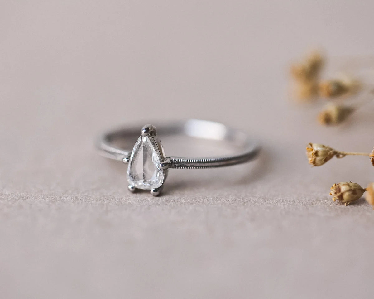 Front view of platinum pear cut diamond ring with fine milled edge