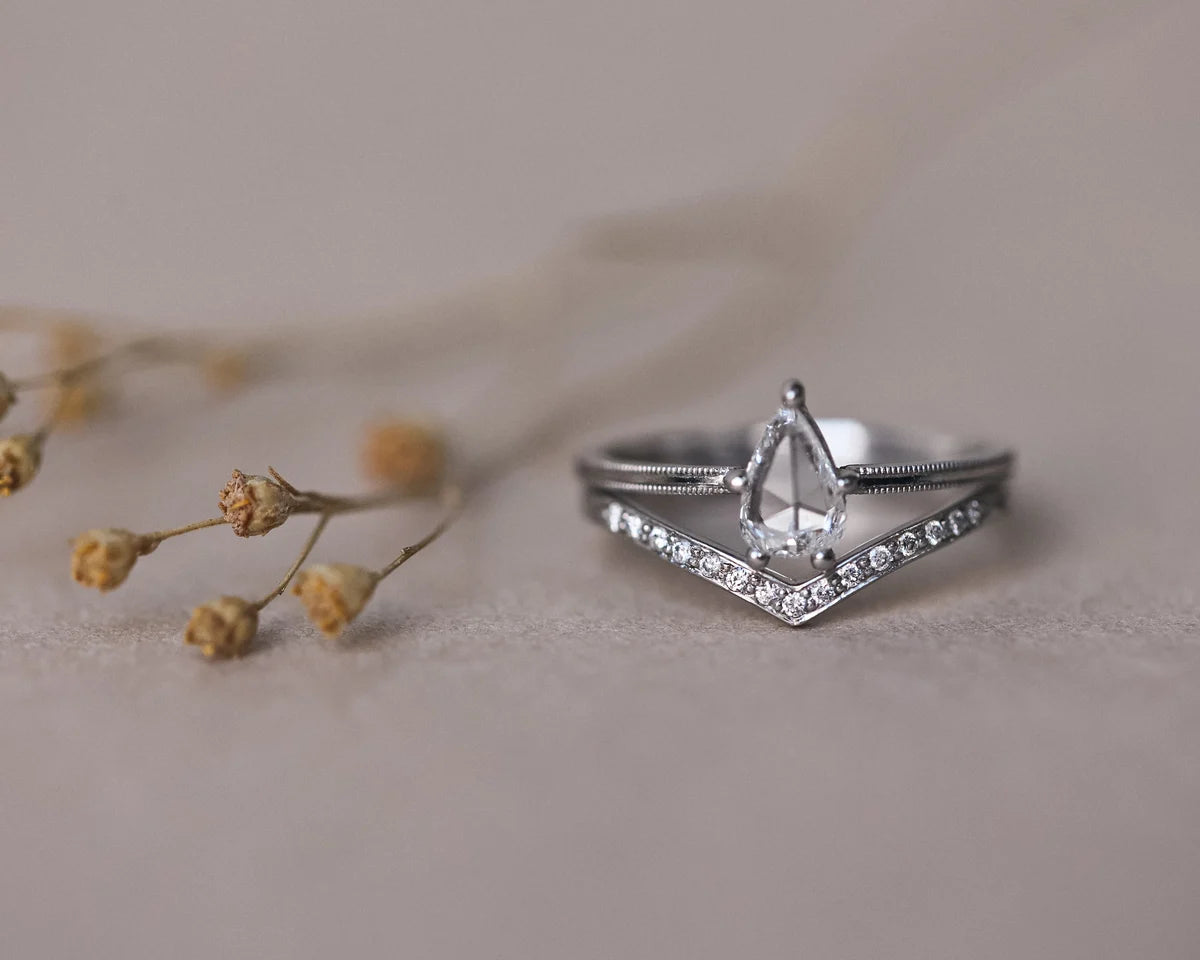 Platinum pear diamond ring paired with pavé wishbone wedding band