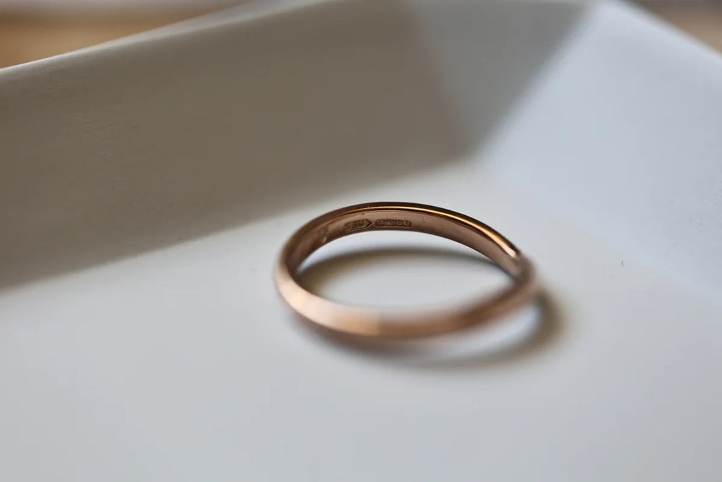 Minimal 2mm rose gold wishbone ring on white ceramic dish