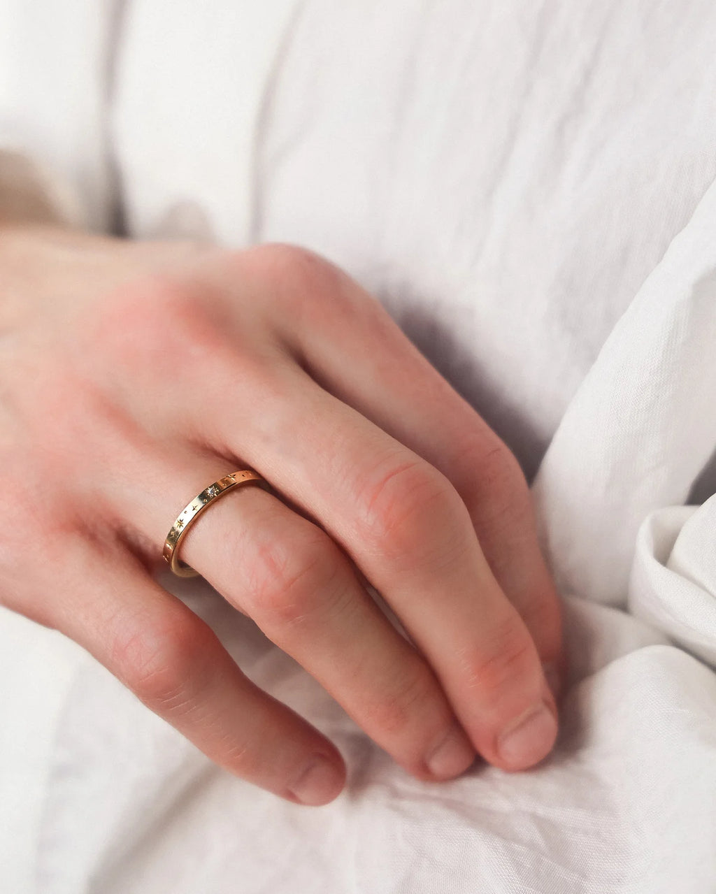 Star set diamond eternity ring worn on hand with white shirt