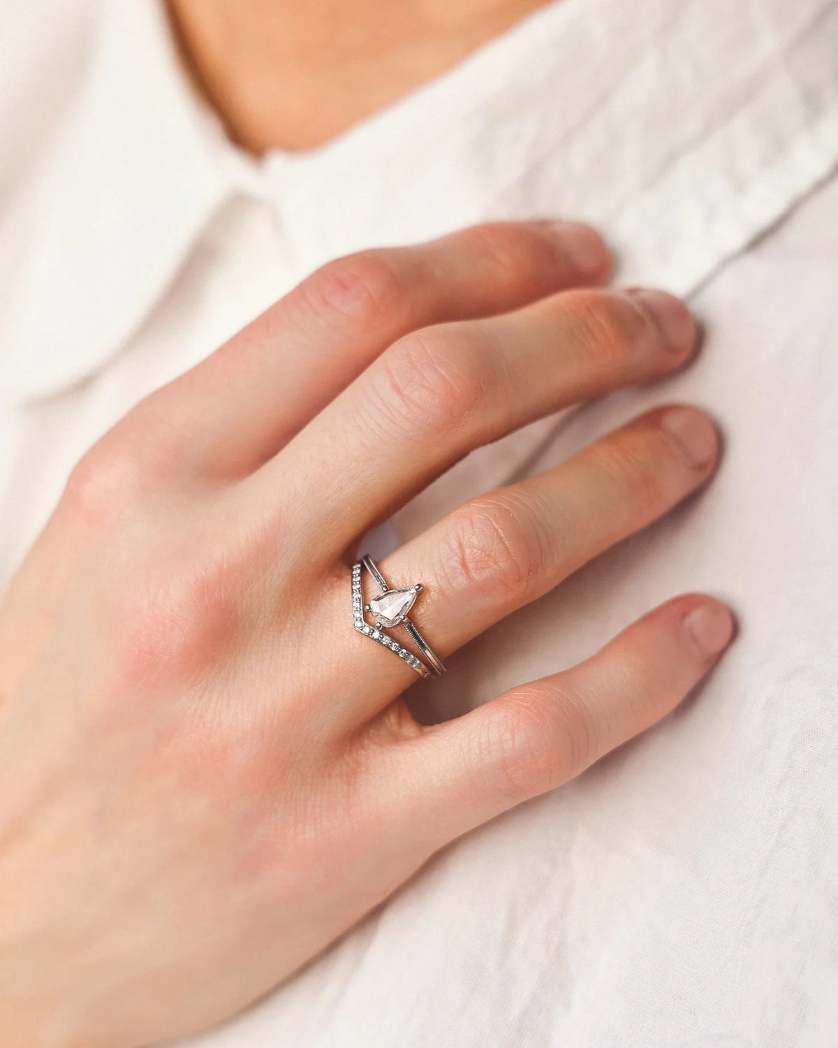 Pear cut diamond ring worn on hand with white shirt