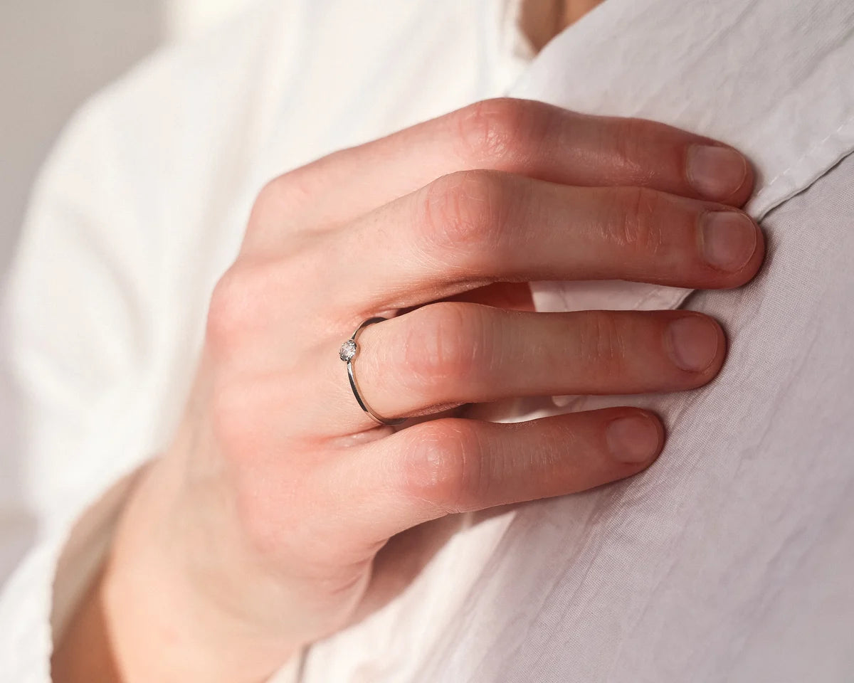 Minimal platinum rose-cut diamond ring worn with white shirt