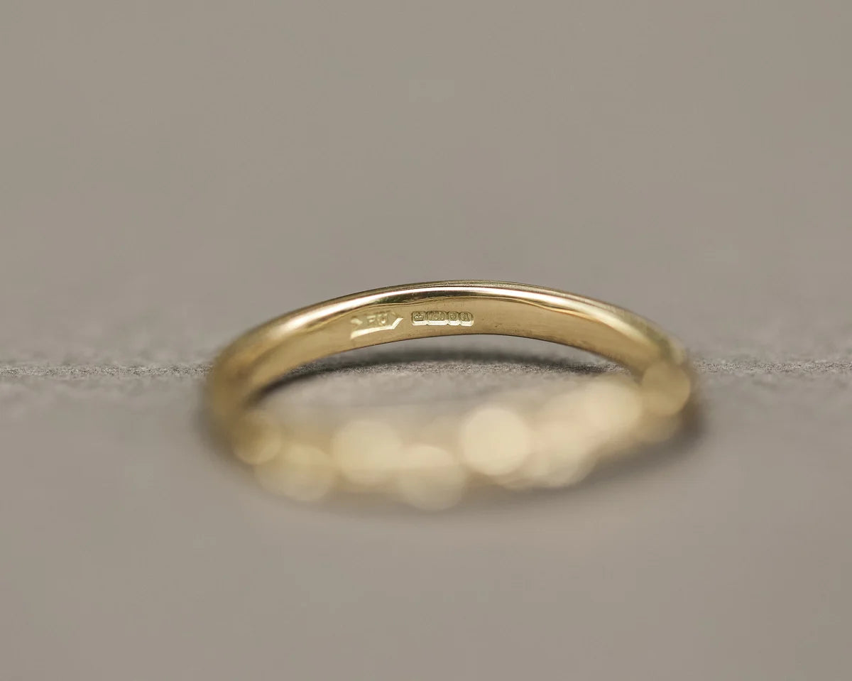 Soft focus view of 2mm yellow gold pressed flower wishbone ring