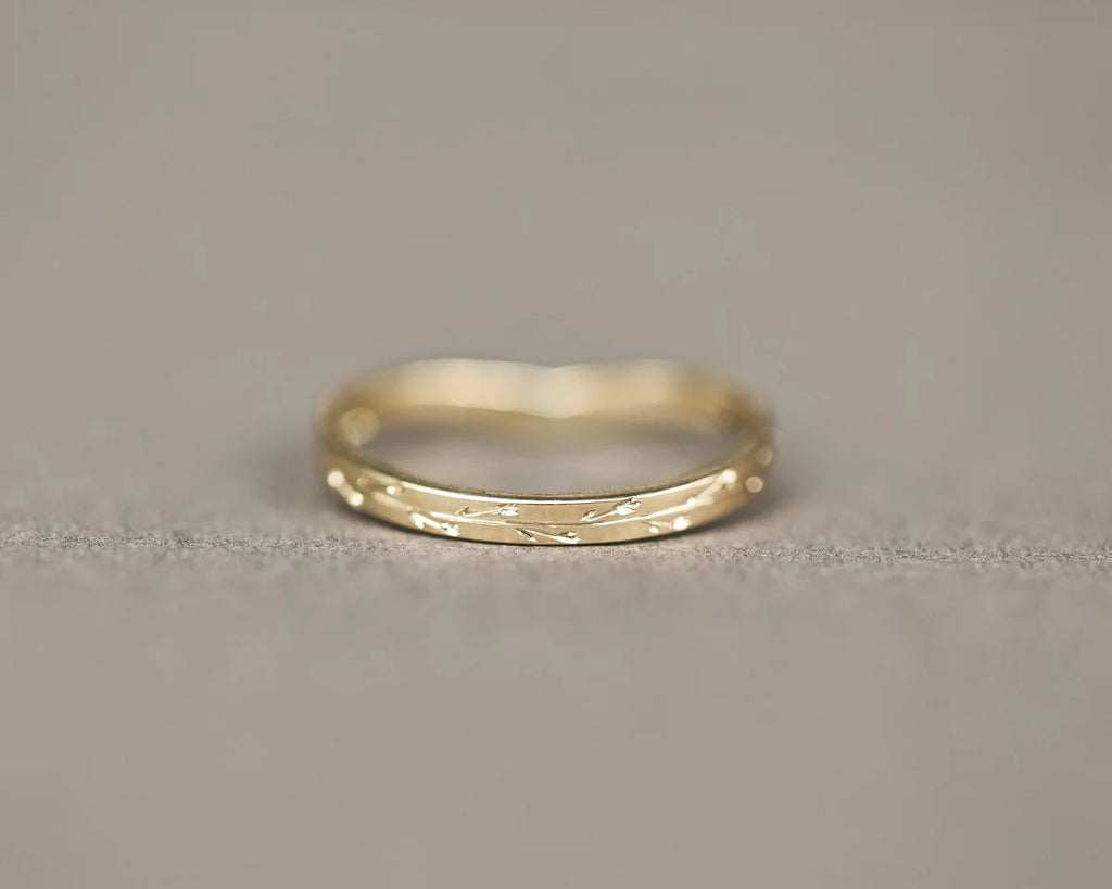 Minimal yellow gold pressed flower wishbone ring on neutral background