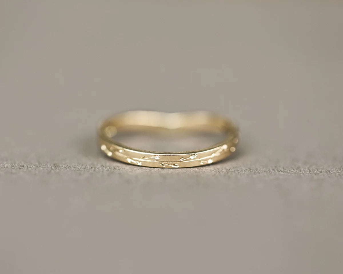 Minimal yellow gold pressed flower wishbone ring on neutral background
