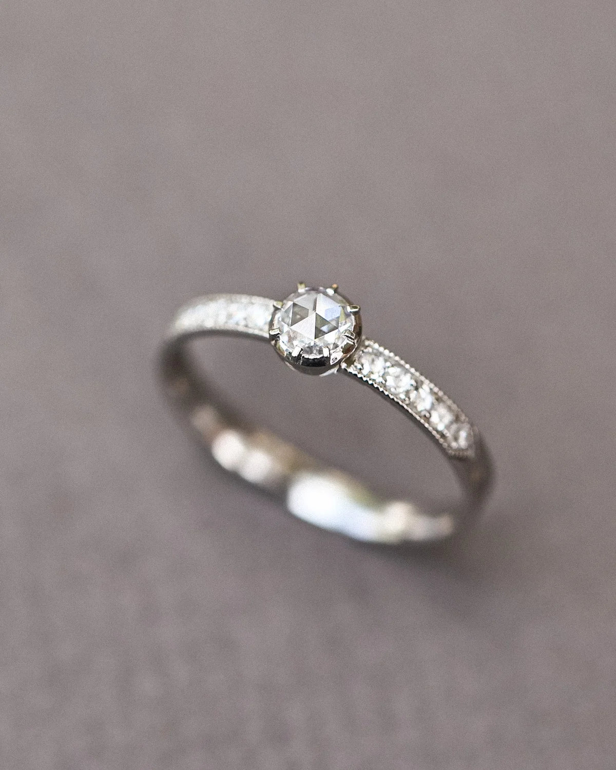 Close-up of a platinum rose-cut diamond ring with pavé band