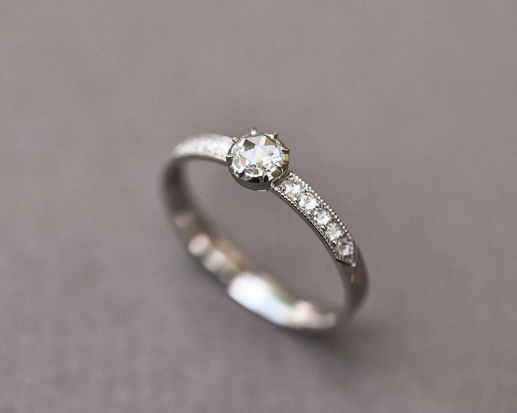 Refined platinum solitaire ring with pavé diamond shoulders