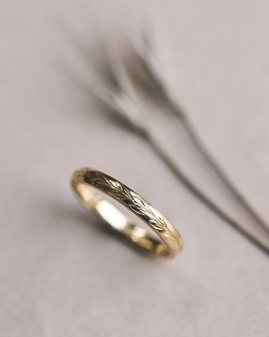 Close-up of hand engraved olive leaf detail on 18ct yellow gold band