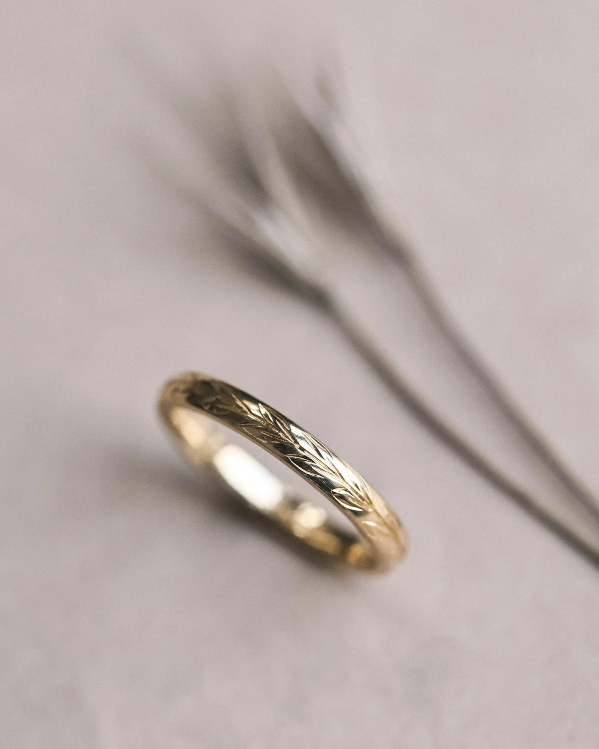 Close-up of hand engraved olive leaf detail on 18ct yellow gold band