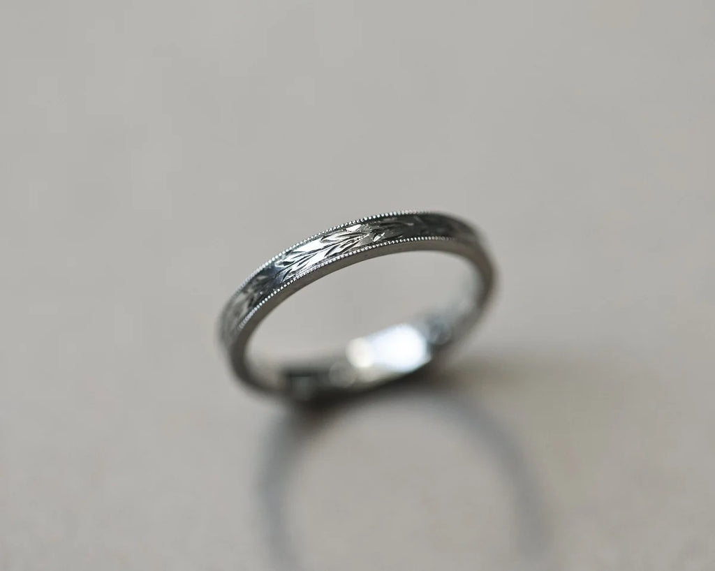 Angled view of handmade platinum olive leaf engraved wedding ring
