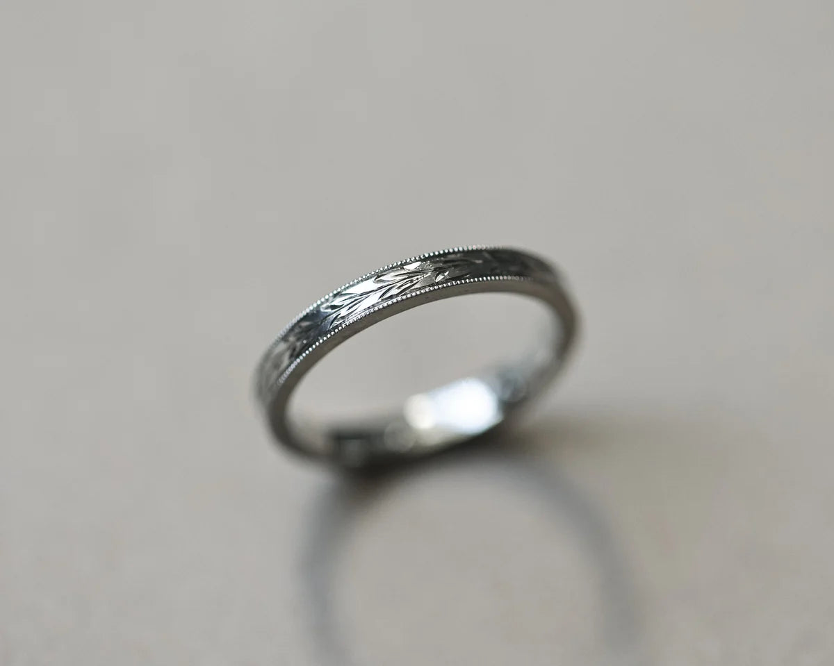 Angled view of handmade platinum olive leaf engraved wedding ring