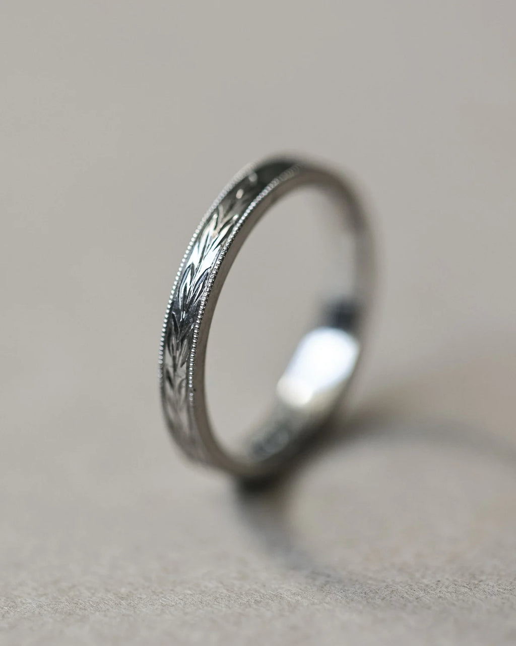 Angled close-up of platinum olive leaf engraved wedding band