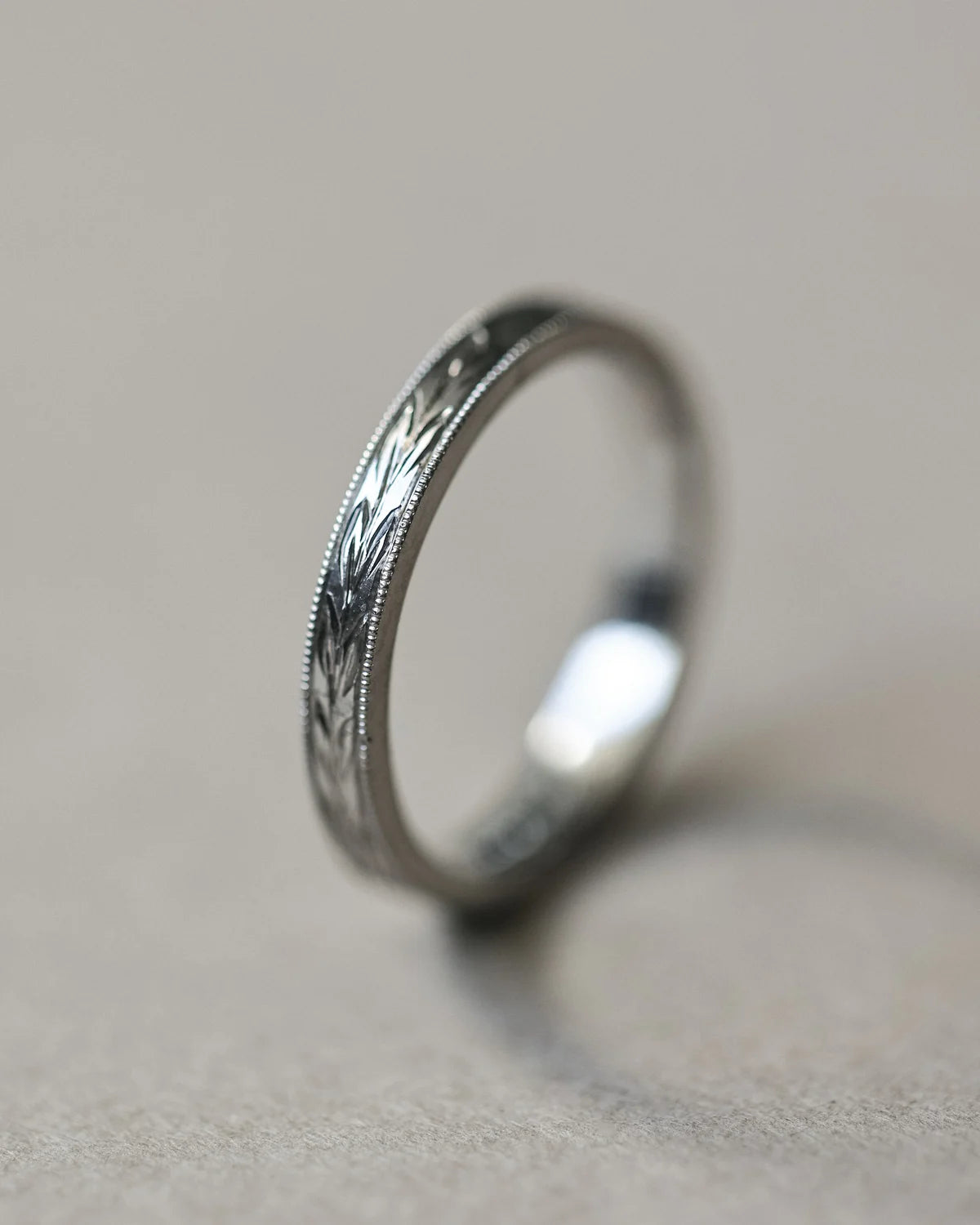 Angled close-up of platinum olive leaf engraved wedding band
