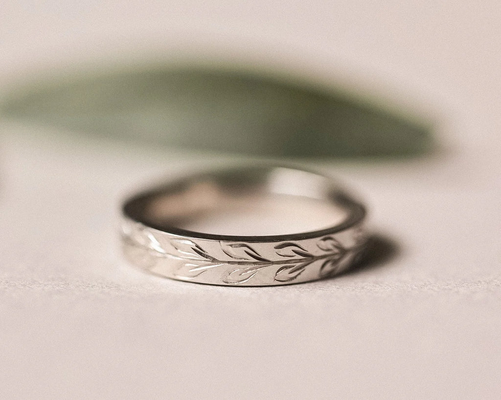 Close-up of matte olive leaf engraved wedding ring in platinum