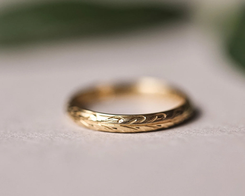 Close-up of 9ct yellow gold wedding ring with hand engraved olive leaf motif