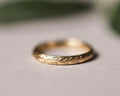 Close-up of 9ct yellow gold wedding ring with hand engraved olive leaf motif