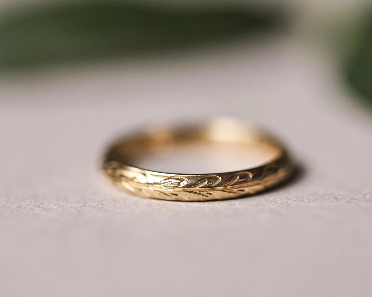 Close-up of 9ct yellow gold wedding ring with hand engraved olive leaf motif