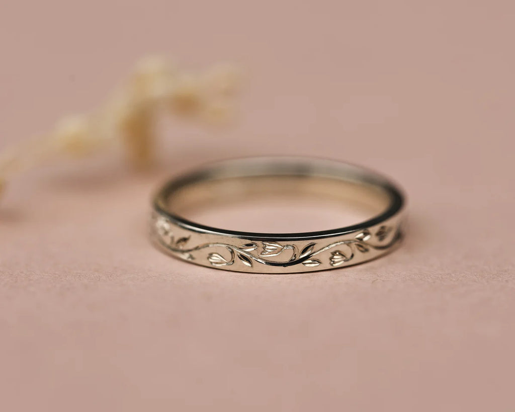 Close-up of platinum wedding band with hand engraved snowdrop motif