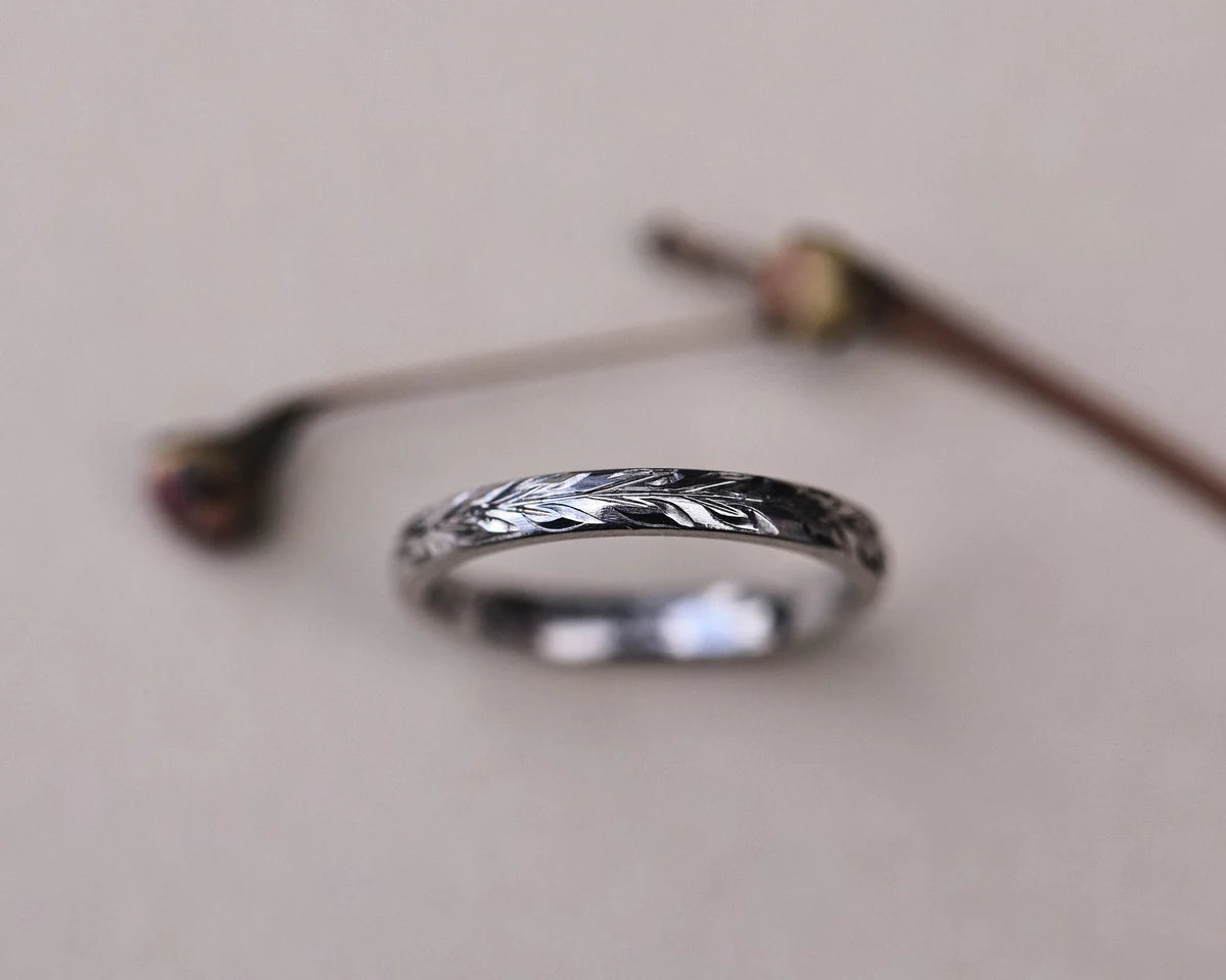 Detailed view of hand engraved olive leaf motif on platinum band
