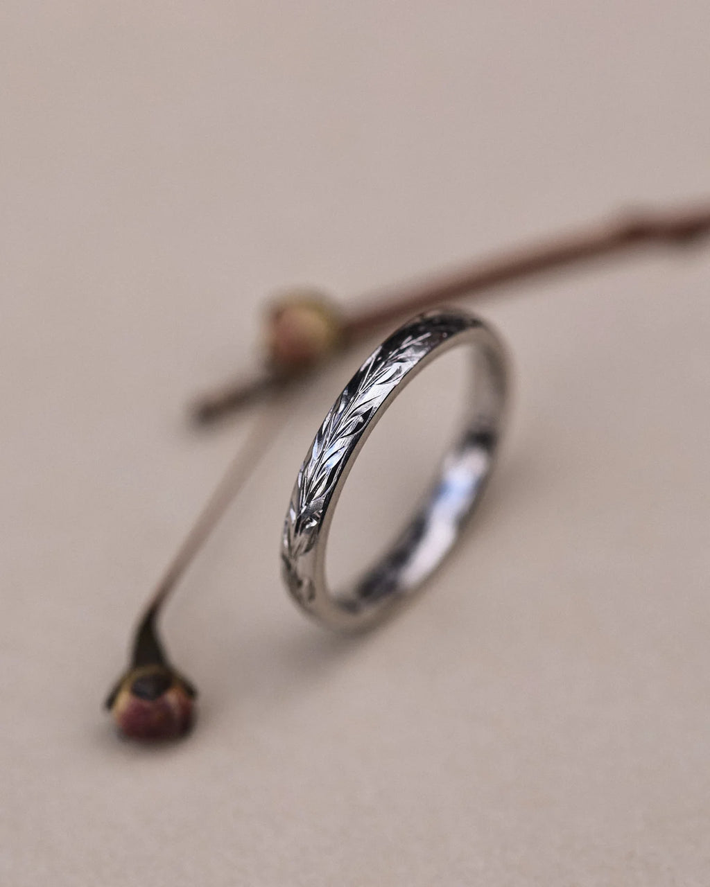 Angled close-up of 2mm platinum olive leaf engraved ring