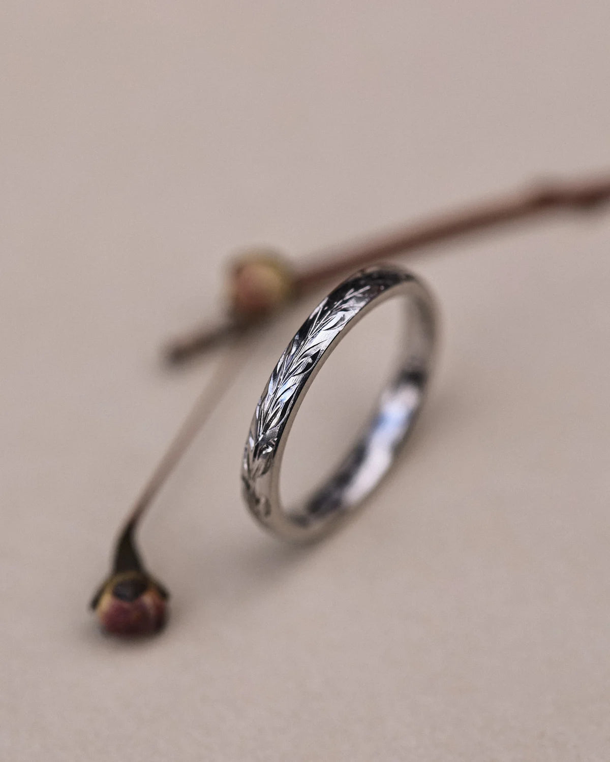 Angled close-up of 2mm platinum olive leaf engraved ring