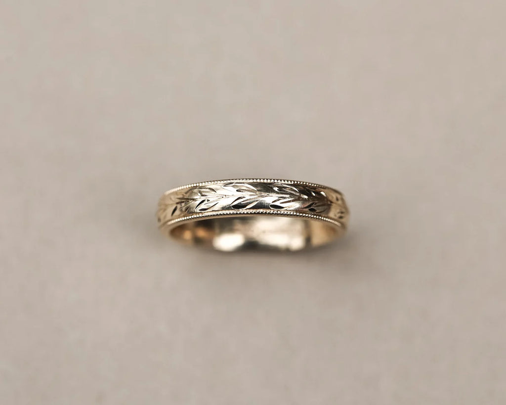 Low front view of olive leaf and milled edge wedding ring in yellow gold