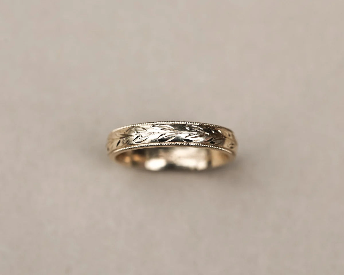 Low front view of olive leaf and milled edge wedding ring in yellow gold