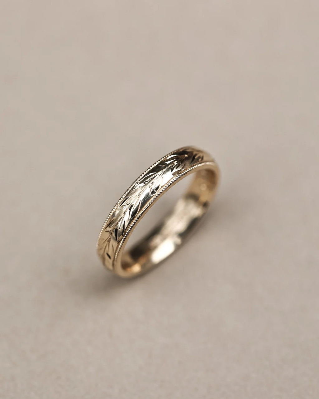 Angled close-up of handmade olive leaf and milled edge ring