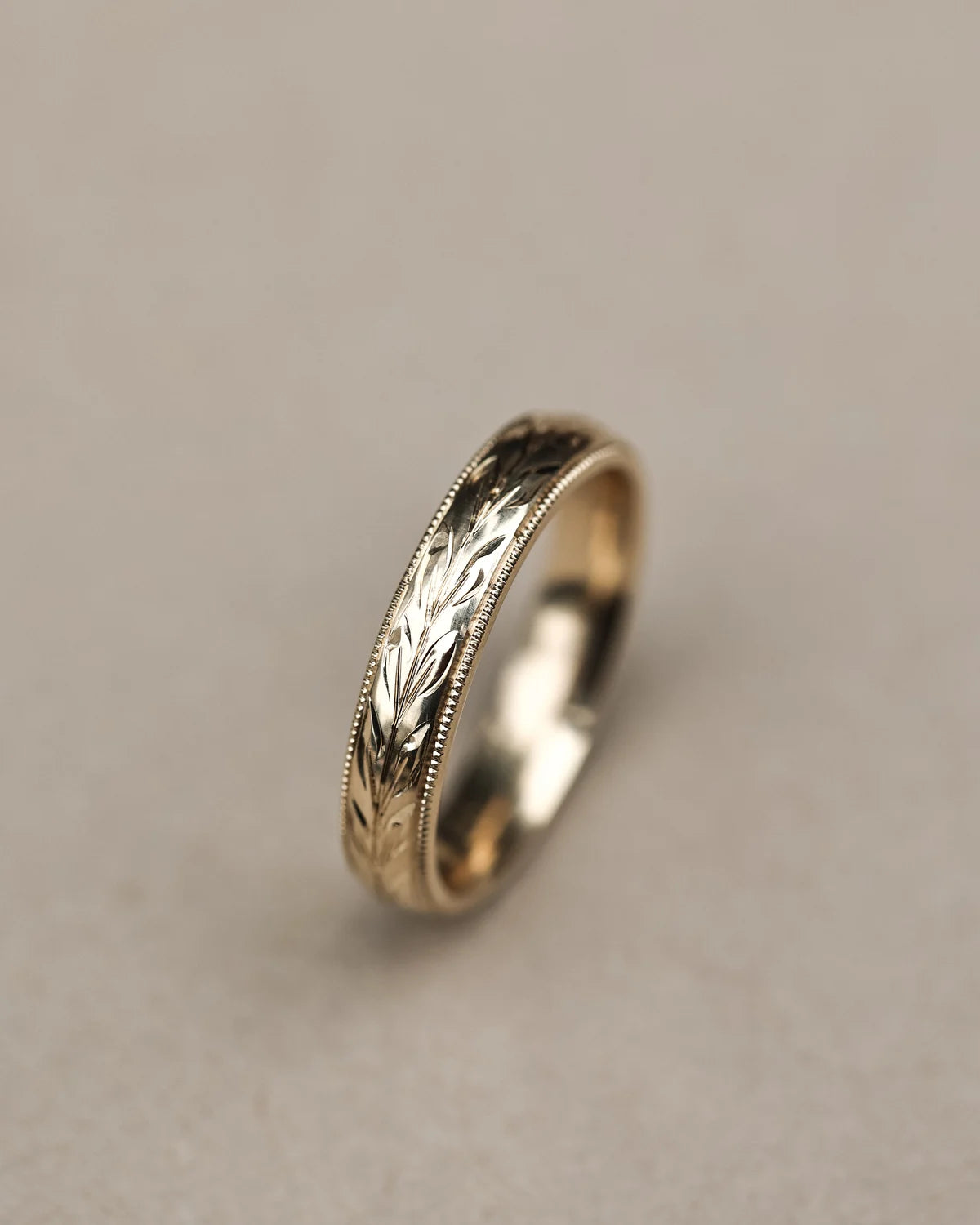 Vertical view of 4mm yellow gold olive leaf and milled edge ring