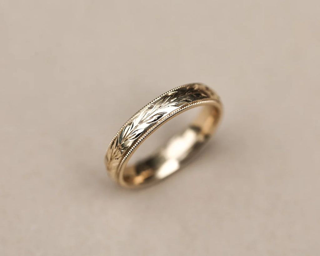 Angled view of 9ct yellow gold olive leaf and milled edge wedding ring