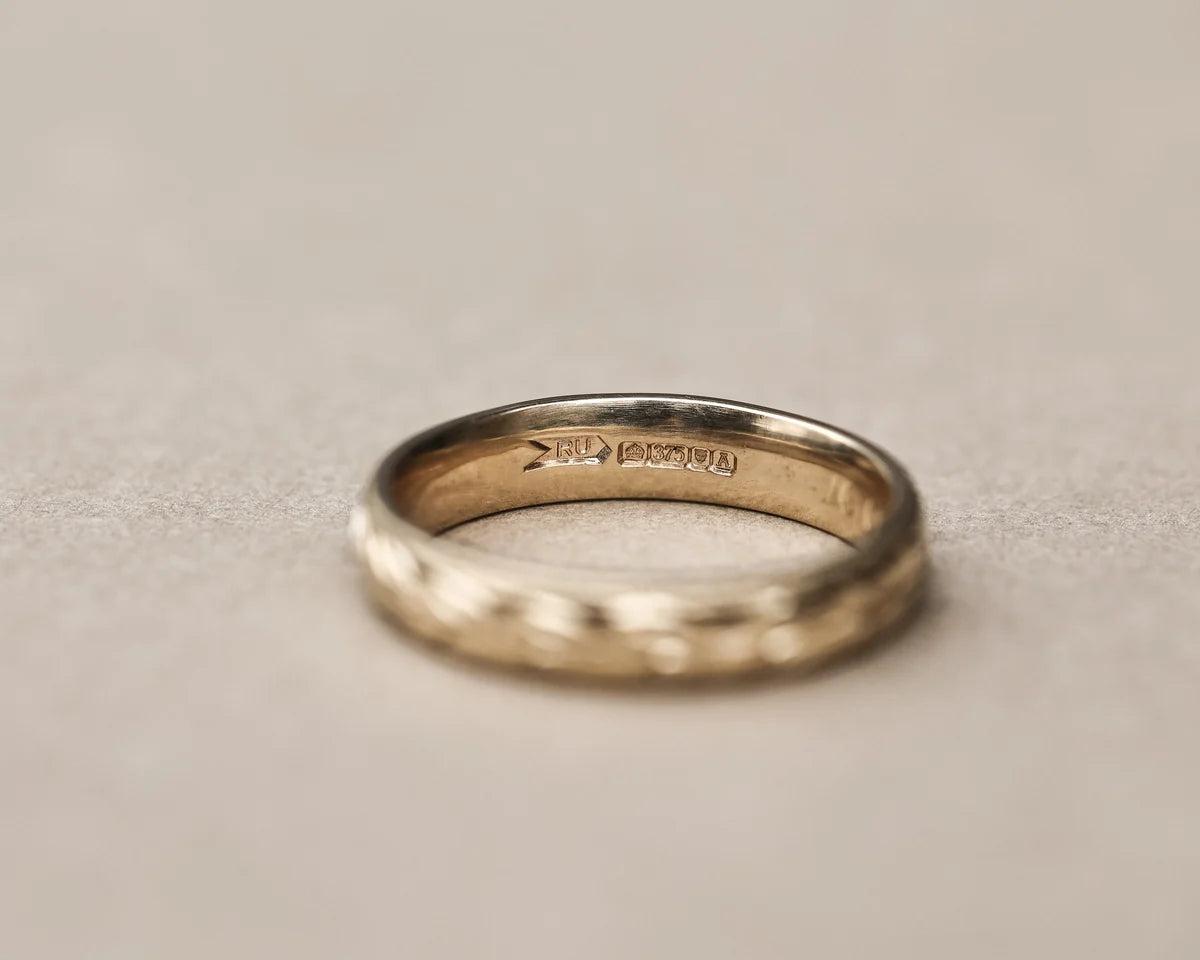 Low front view of olive leaf and milled edge wedding ring in yellow gold