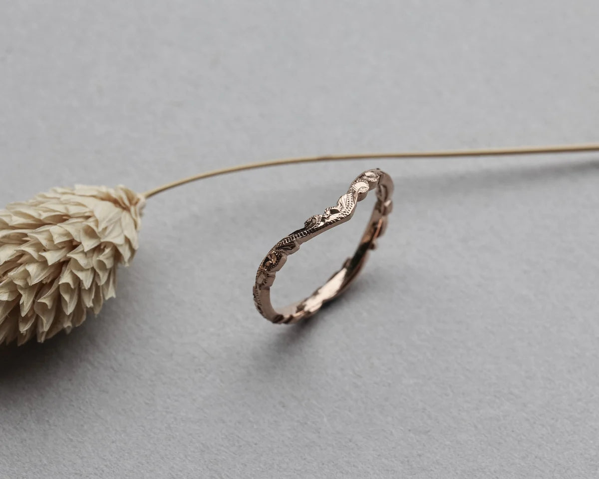 Rose gold ring on a gray background with a dried flower