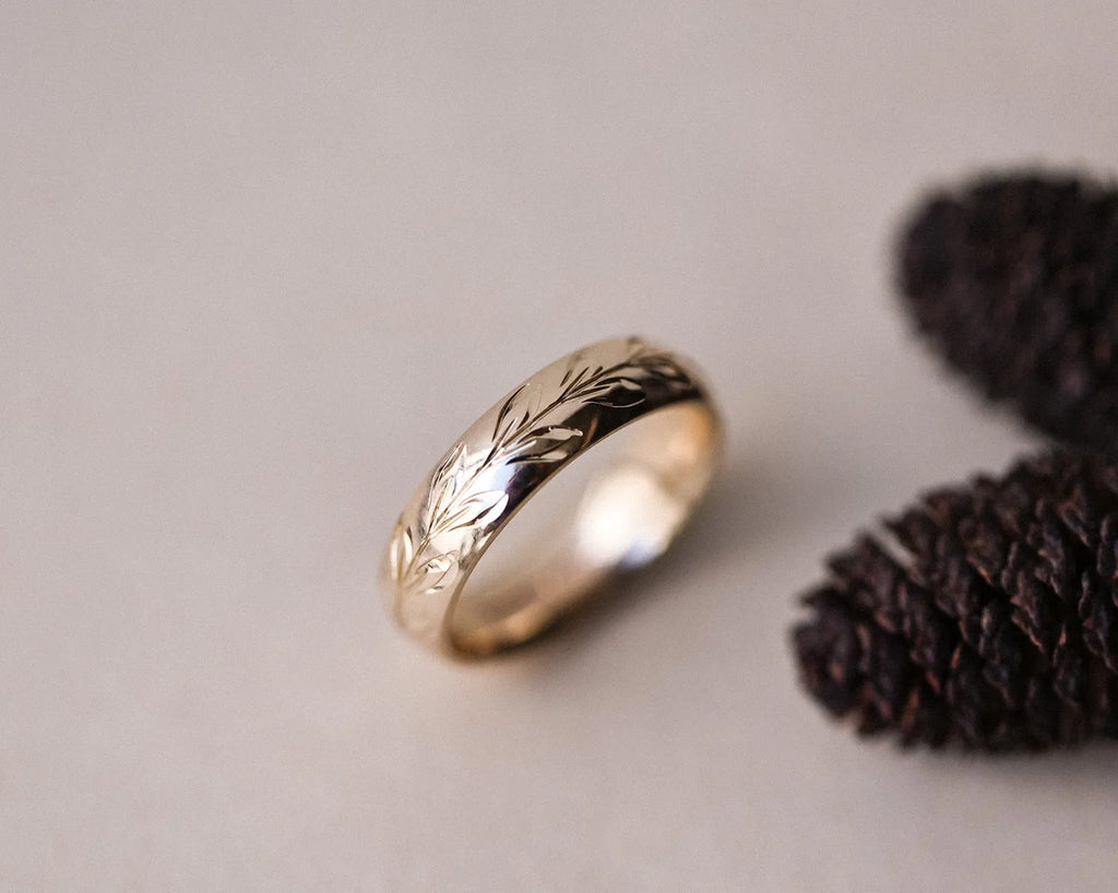 Angled view of olive leaf engraved gold wedding ring with botanical styling
