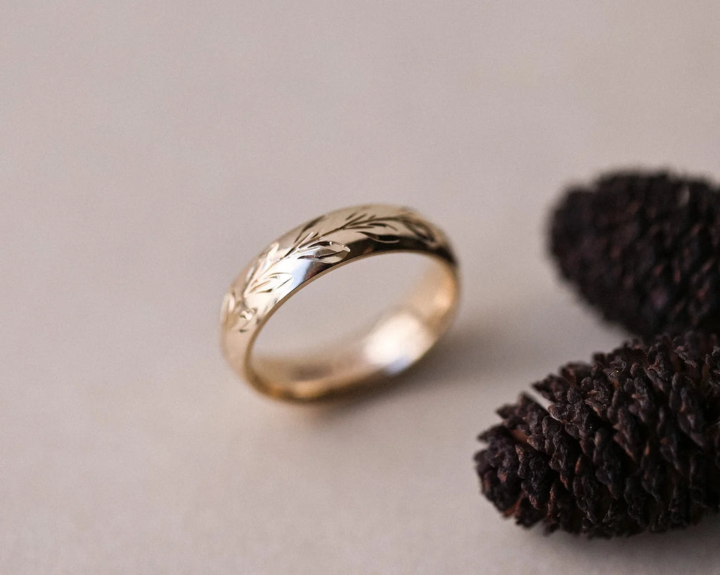 9ct yellow gold olive leaf wedding ring styled with dark botanical detail
