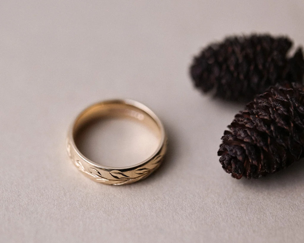 Top view of 5mm yellow gold wedding band with olive leaf engraving